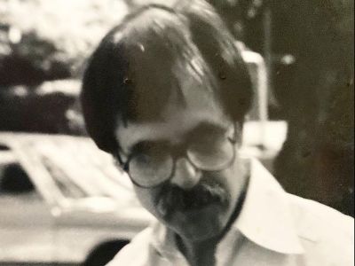 Glenn Cambor is wearing glasses and has a big mustache.